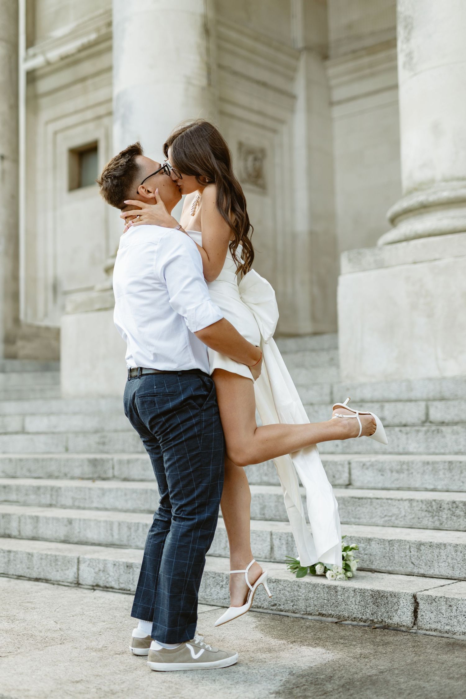 Stylish couple shares intimate moment on grand marble steps of historic building.