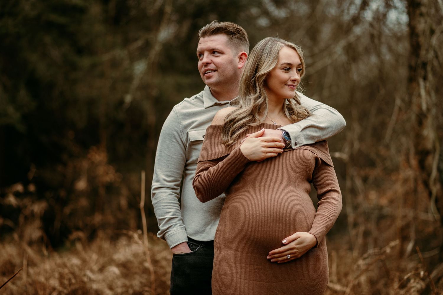 Intimate maternity photos showing a couple's loving embrace in a rustic outdoor setting.