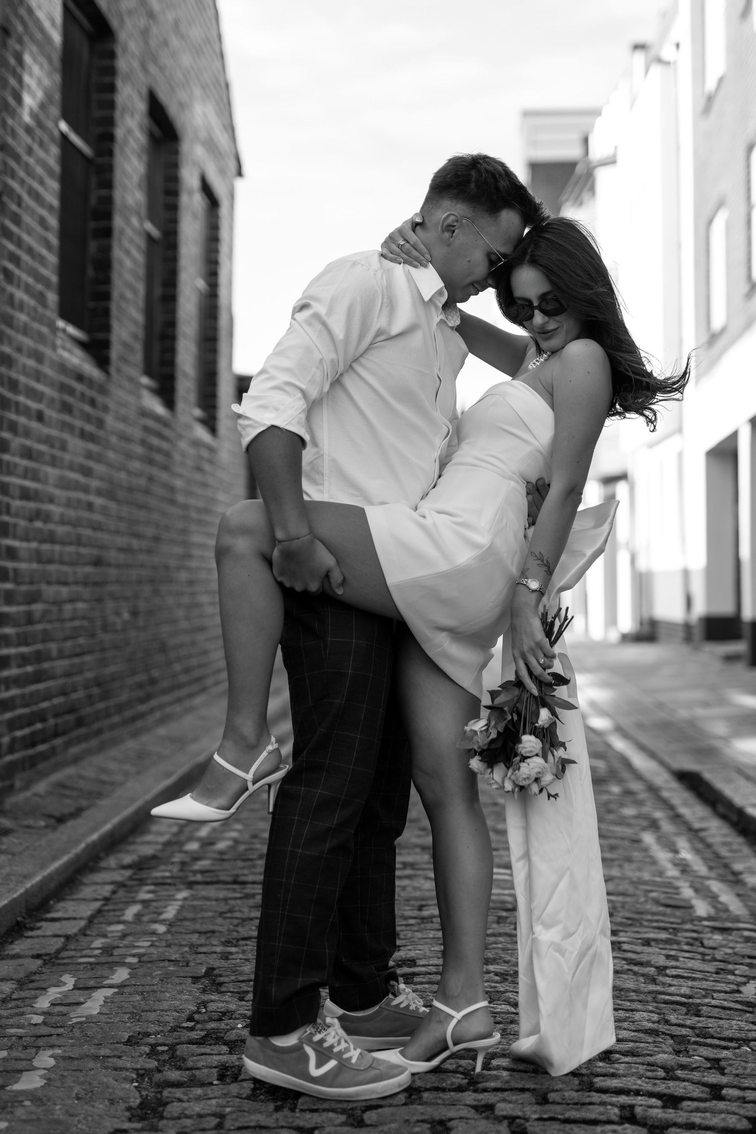 Black and white series shows couple's romantic poses along brick walkway.