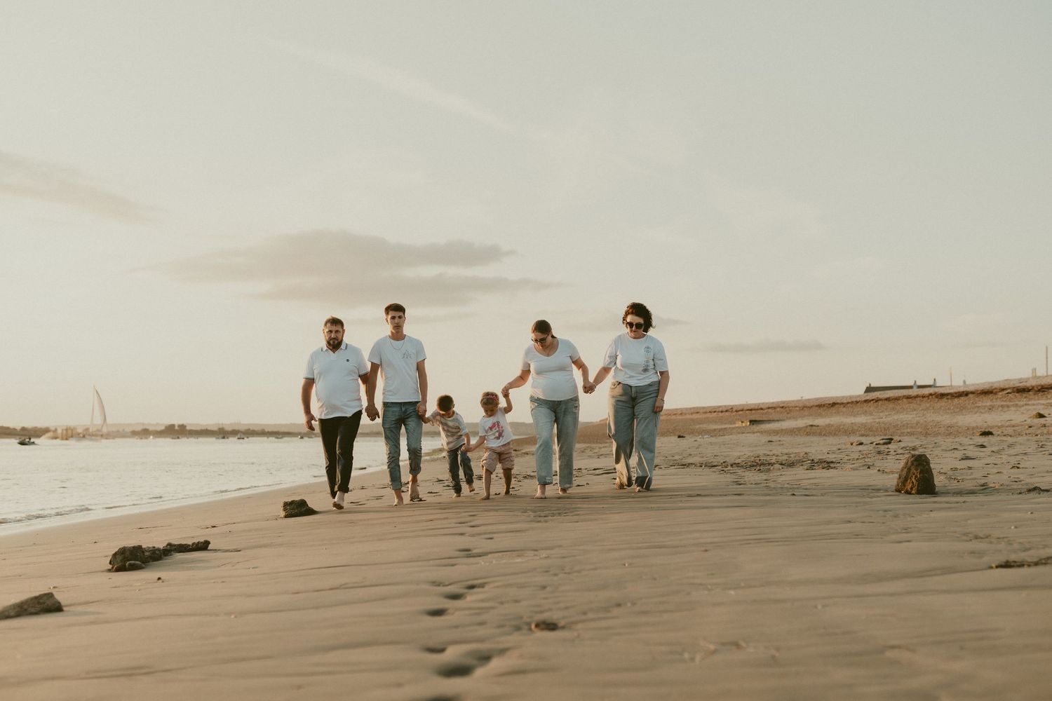 Distant silhouette of family walking along beach horizon at dusk.