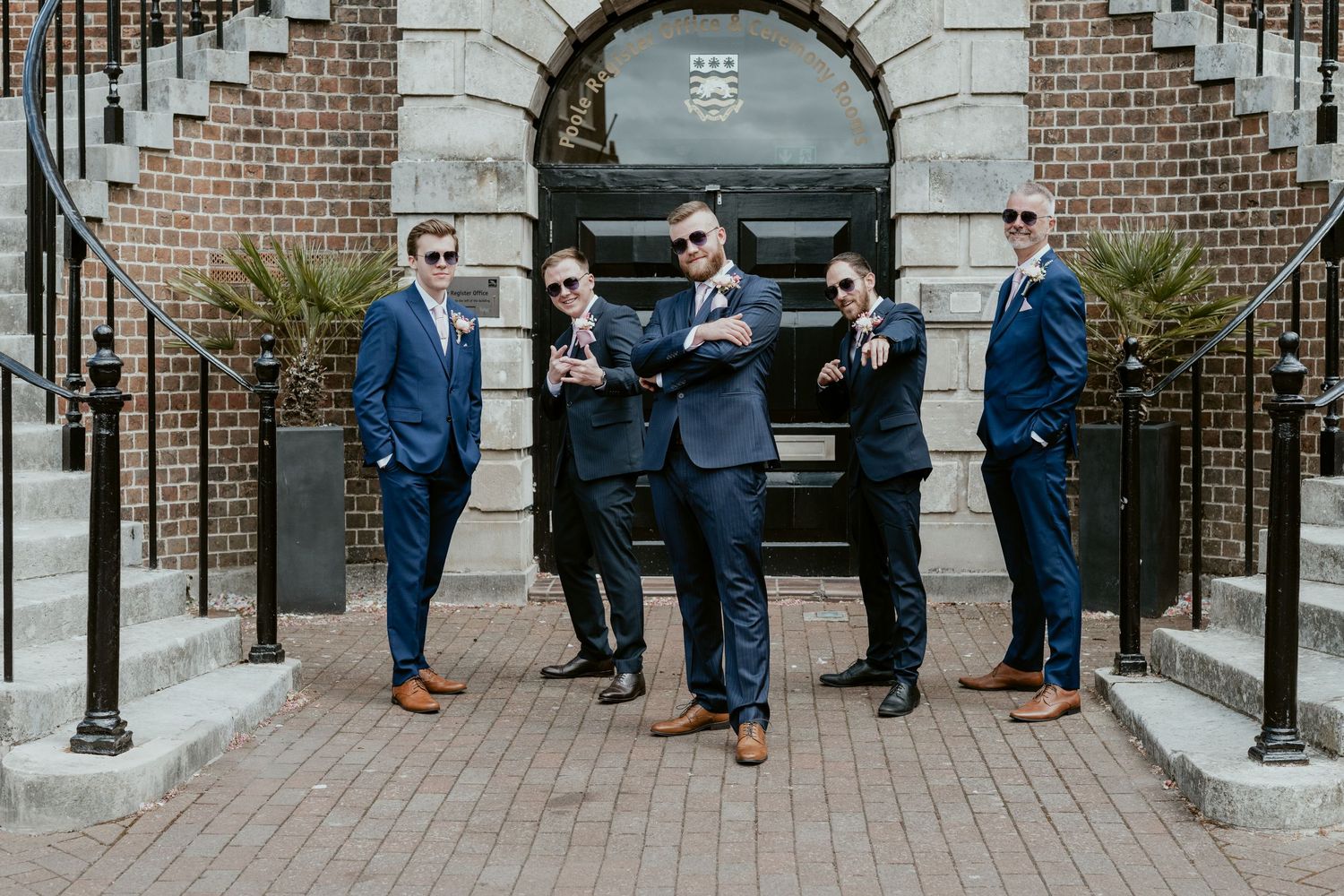 Groomsmen and bridesmaids line up for photos under historic stone archways.