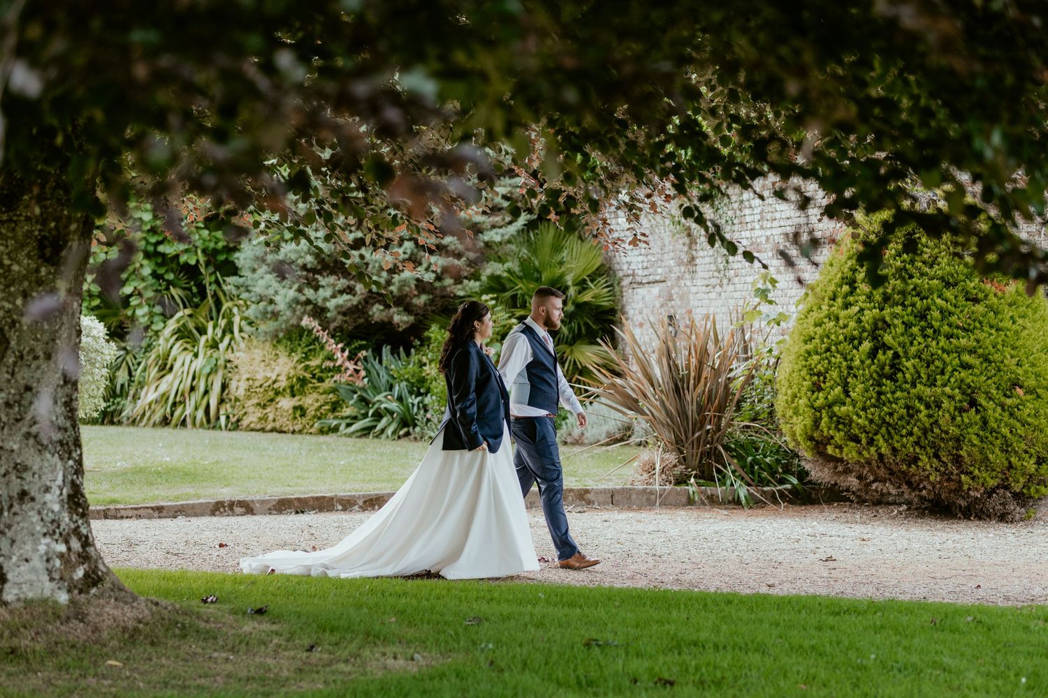 Newlyweds walking through lush garden grounds at their wedding venue.