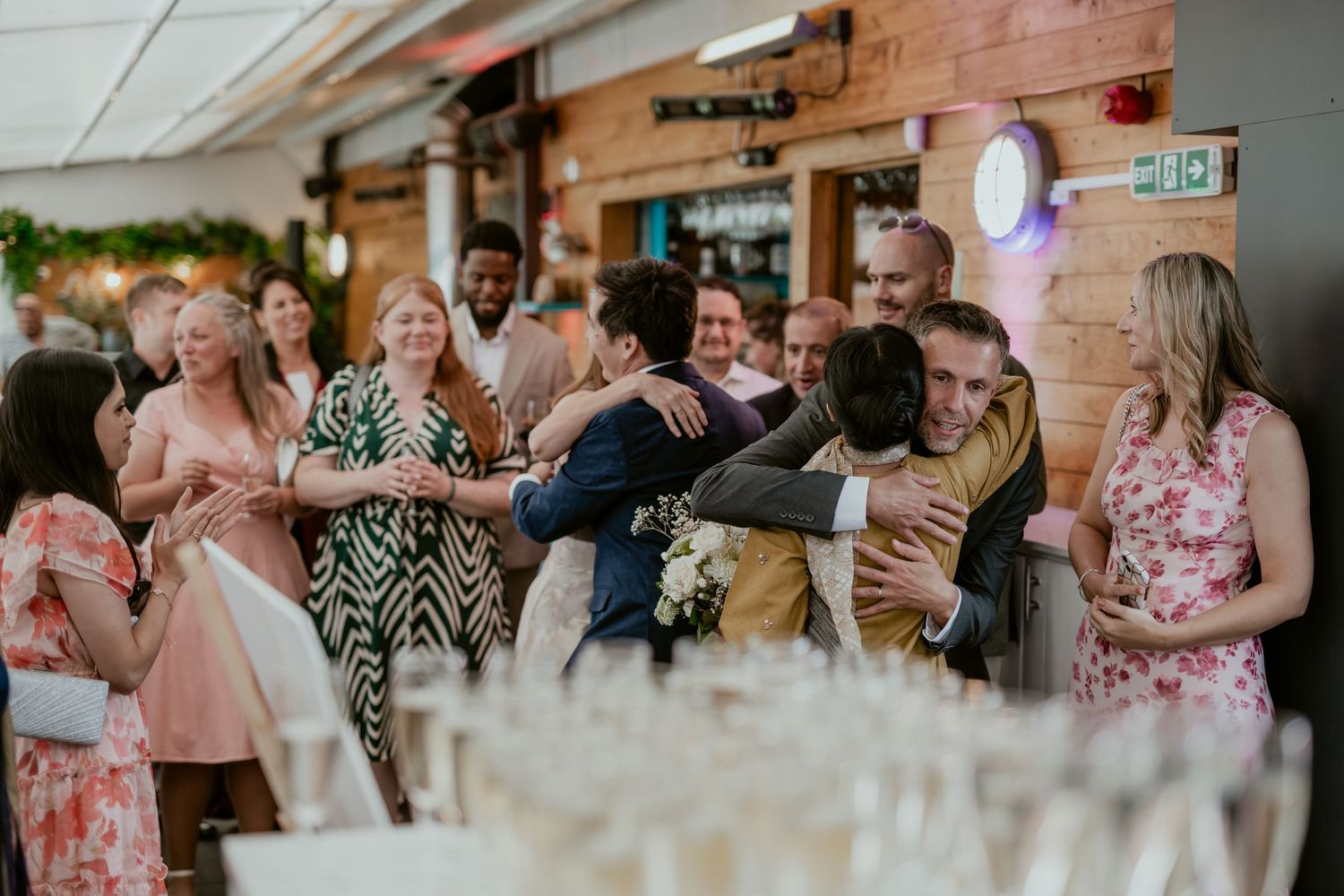 Wedding celebration in rustic venue with guests seated at long tables.