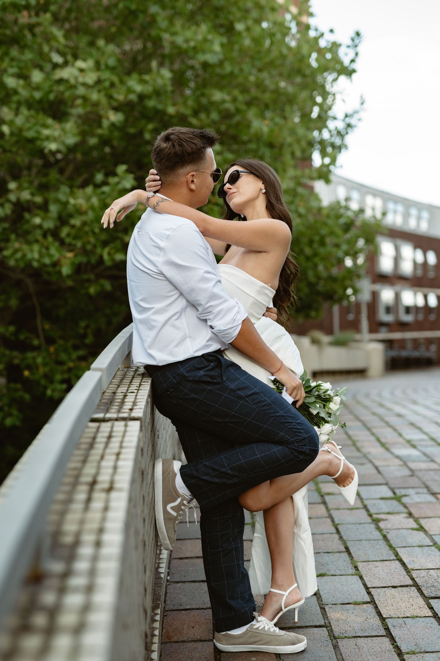 Couple shares playful moments on brick pathway surrounded by greenery.