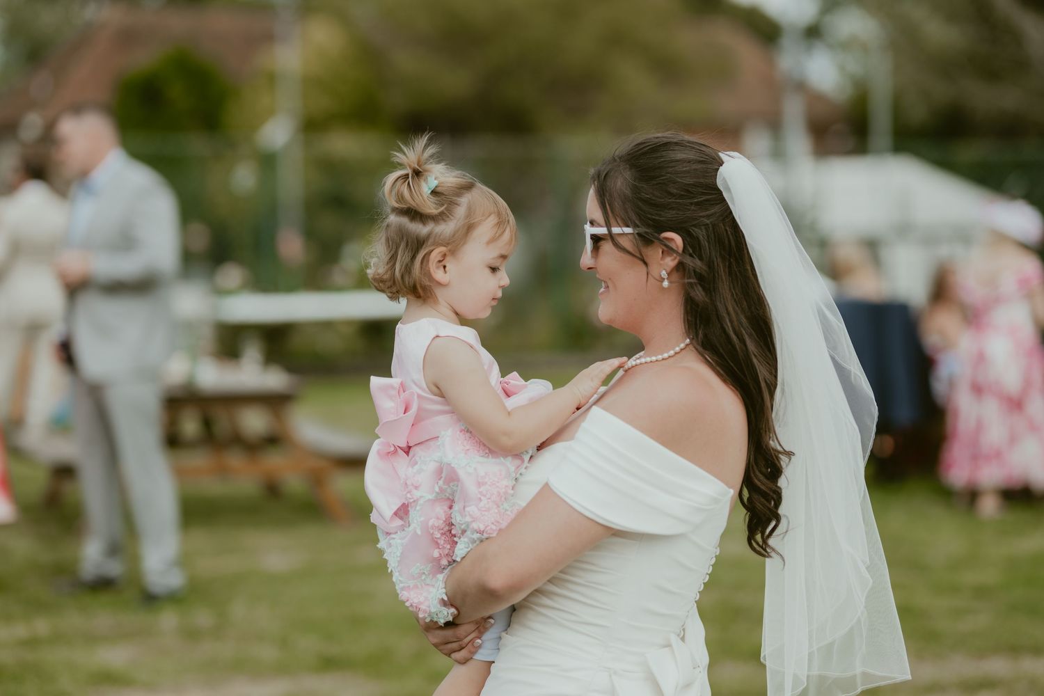 Sweet moment between bride and small child at outdoor wedding reception.