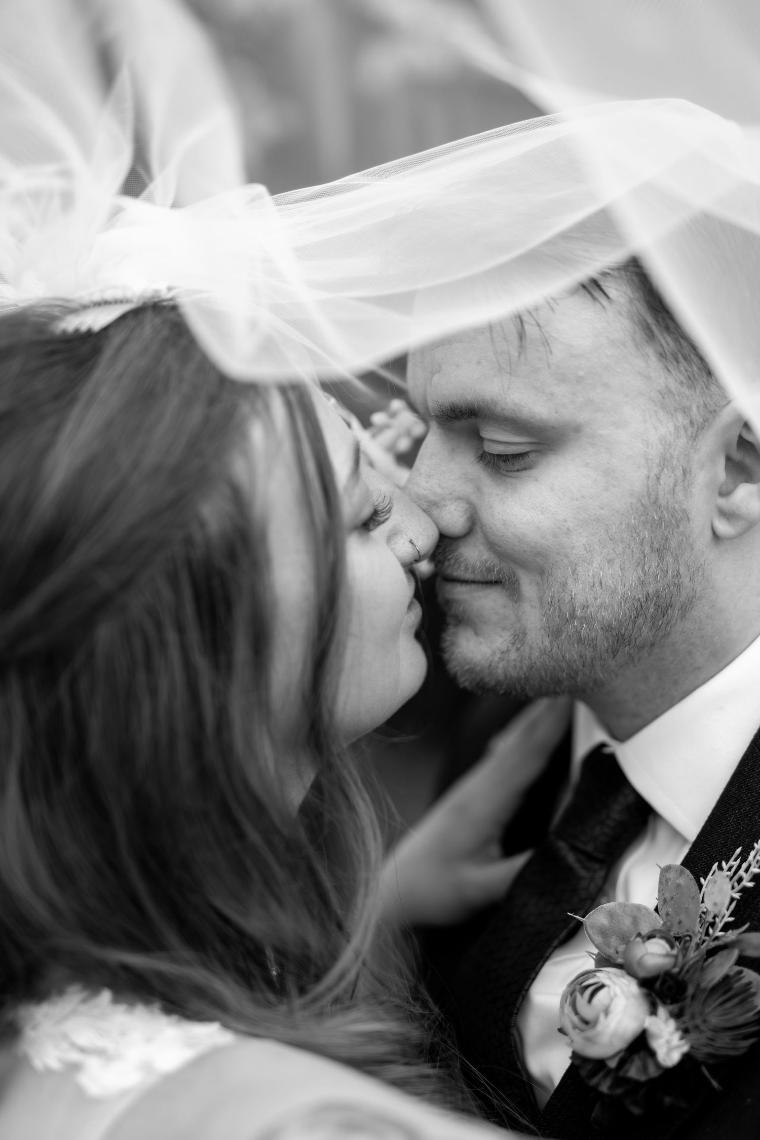 A romantic black and white wedding photo series showing tender kisses between a couple wearing traditional wedding attire.