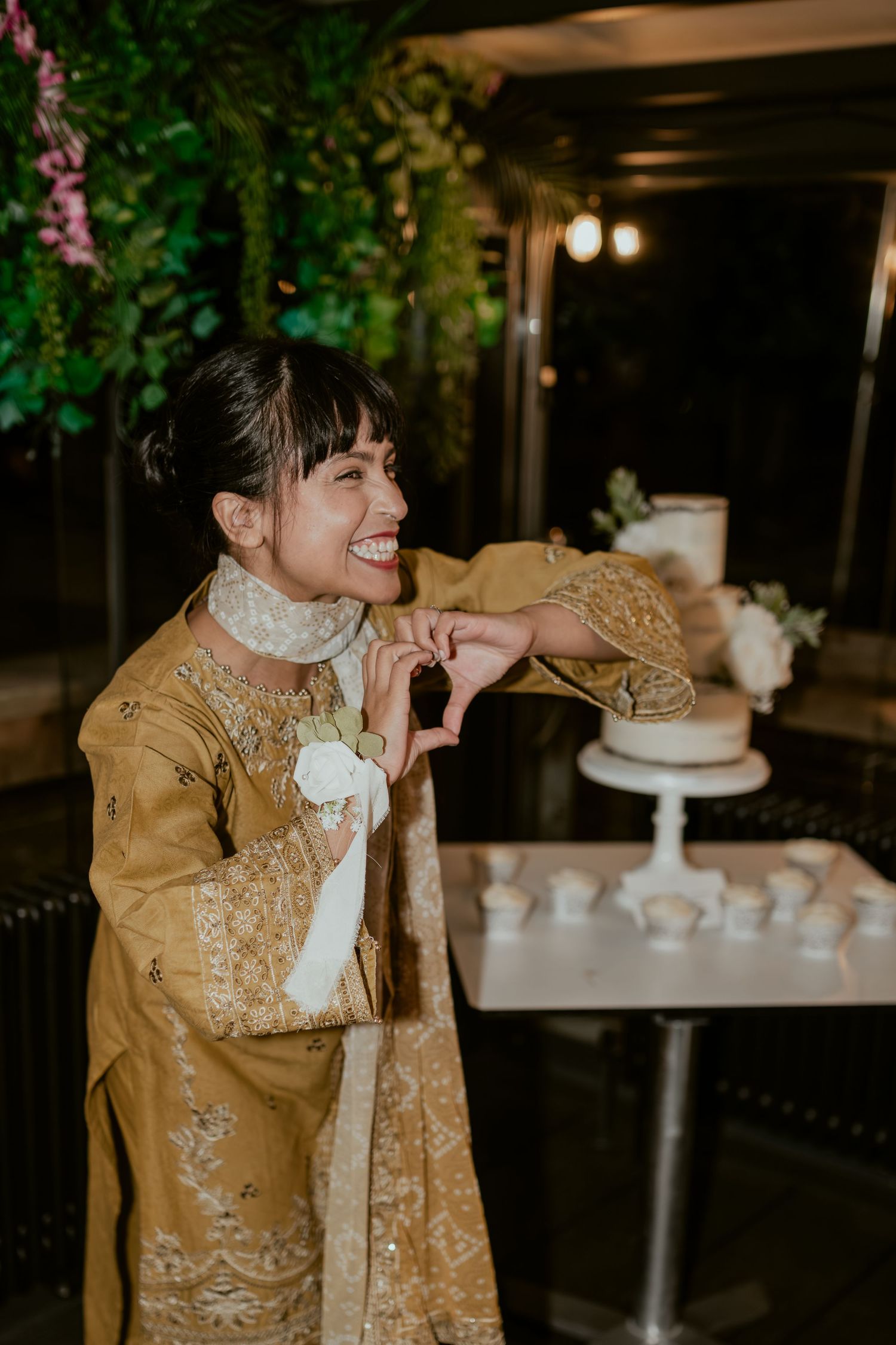 Person in gold embroidered jacket admiring wedding cake at decorated reception.