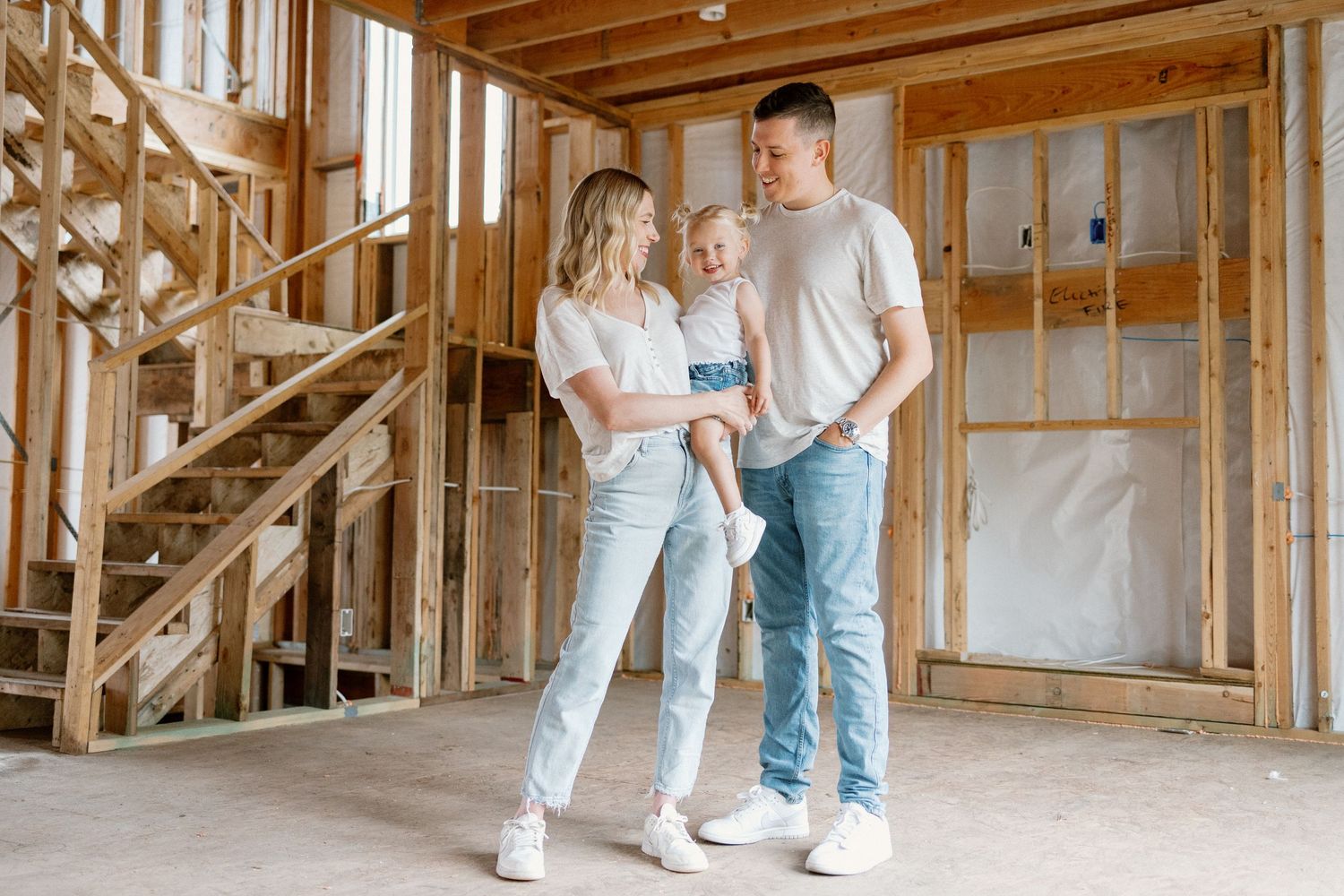 People interacting in an unfinished home interior with exposed wooden beams and natural light.