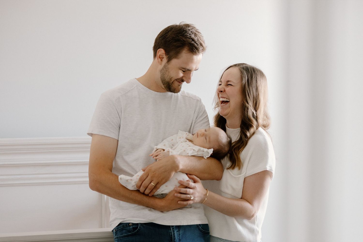 A family shares intimate moments together in a bright, minimalist white room setting.