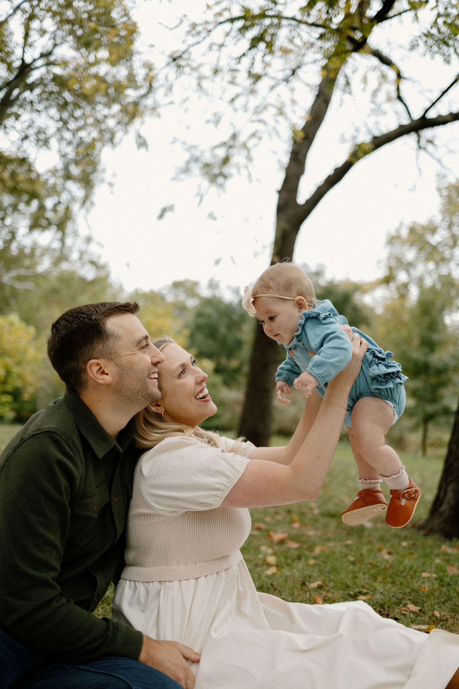 Playful family moments captured outdoors on a blanket during fall season.