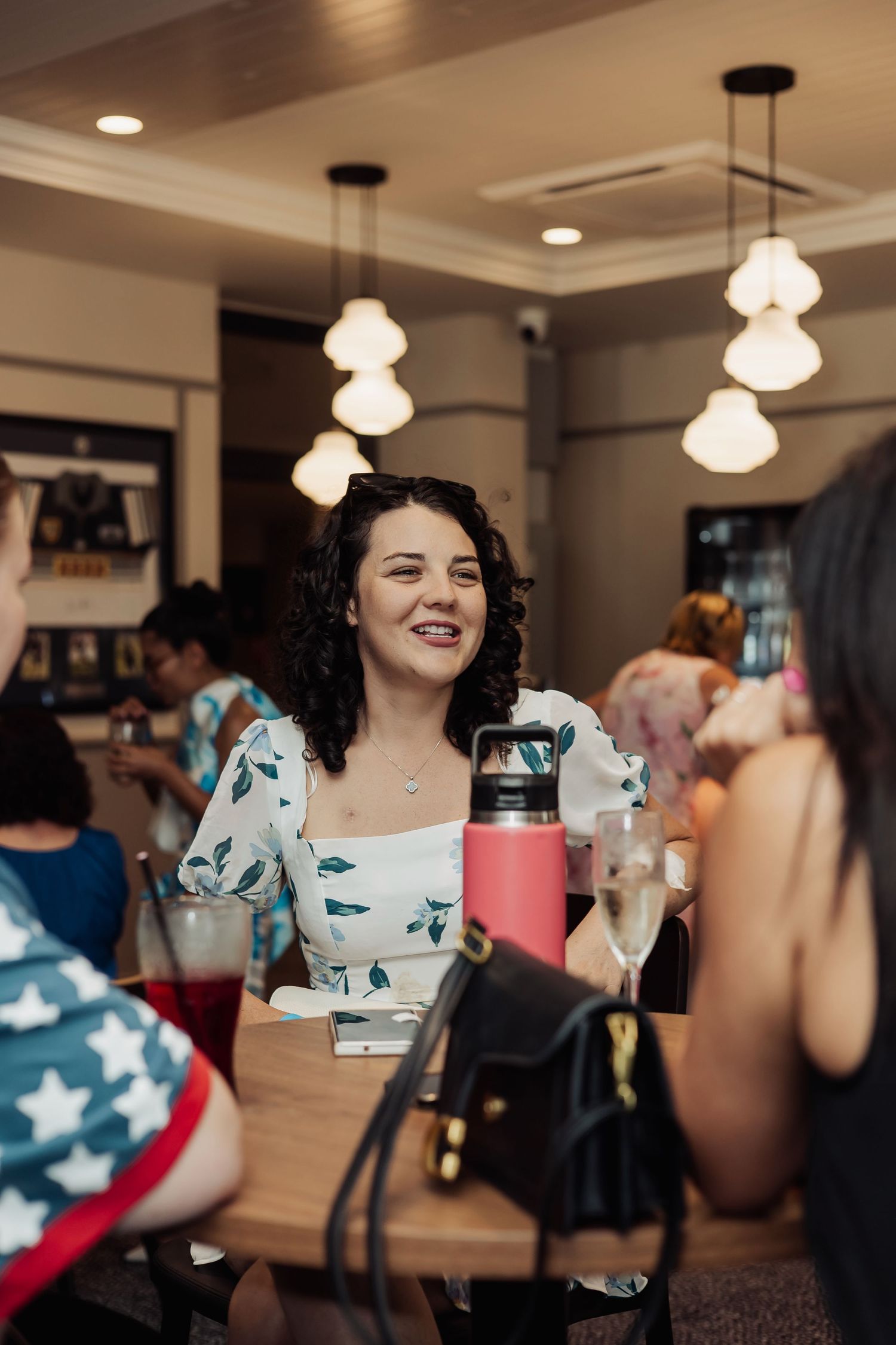 Social gathering in restaurant with pendant lighting and people enjoying conversations.