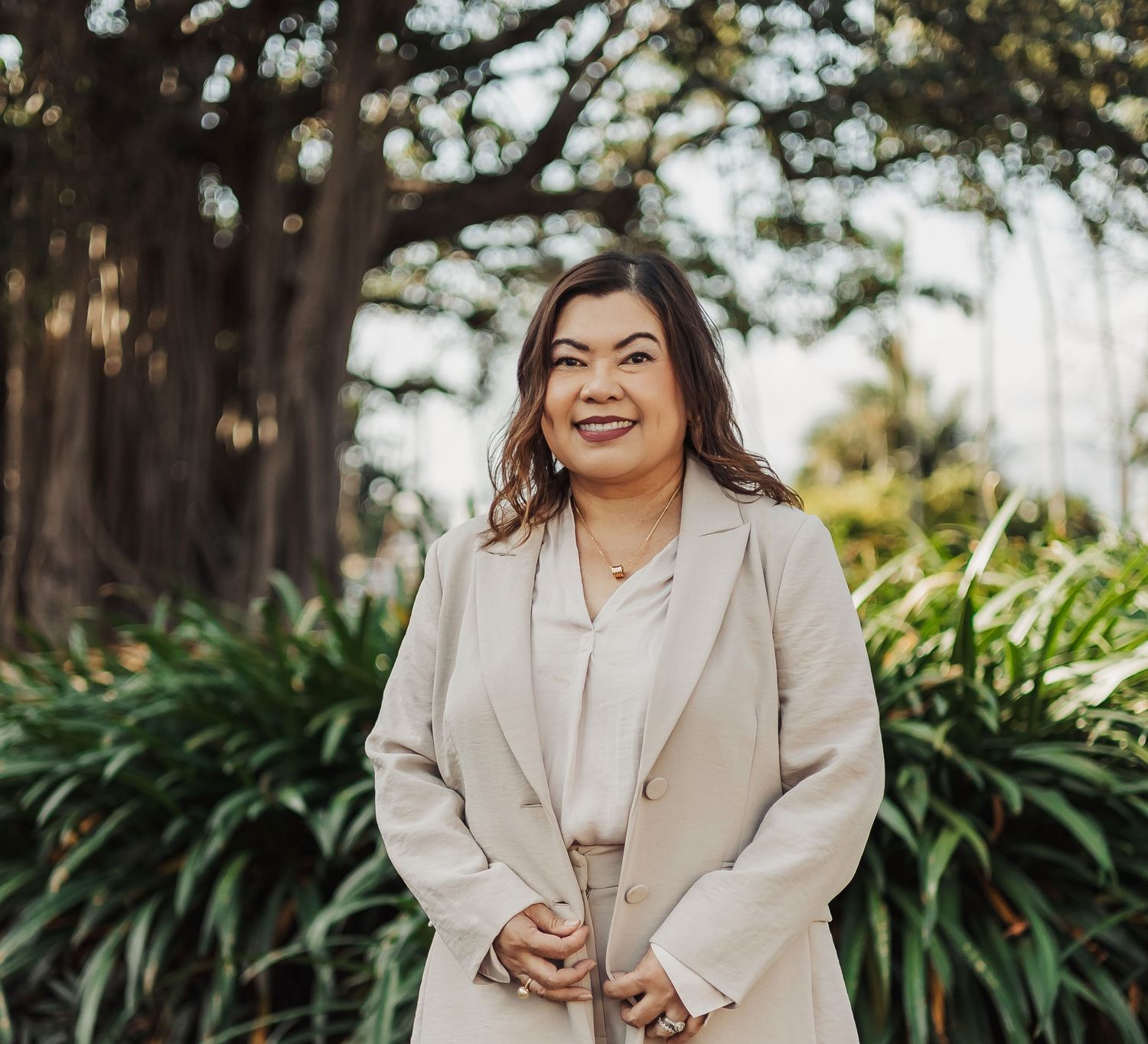 Lifestyle photoshoot outdoors with beige blazer against natural garden backdrop.