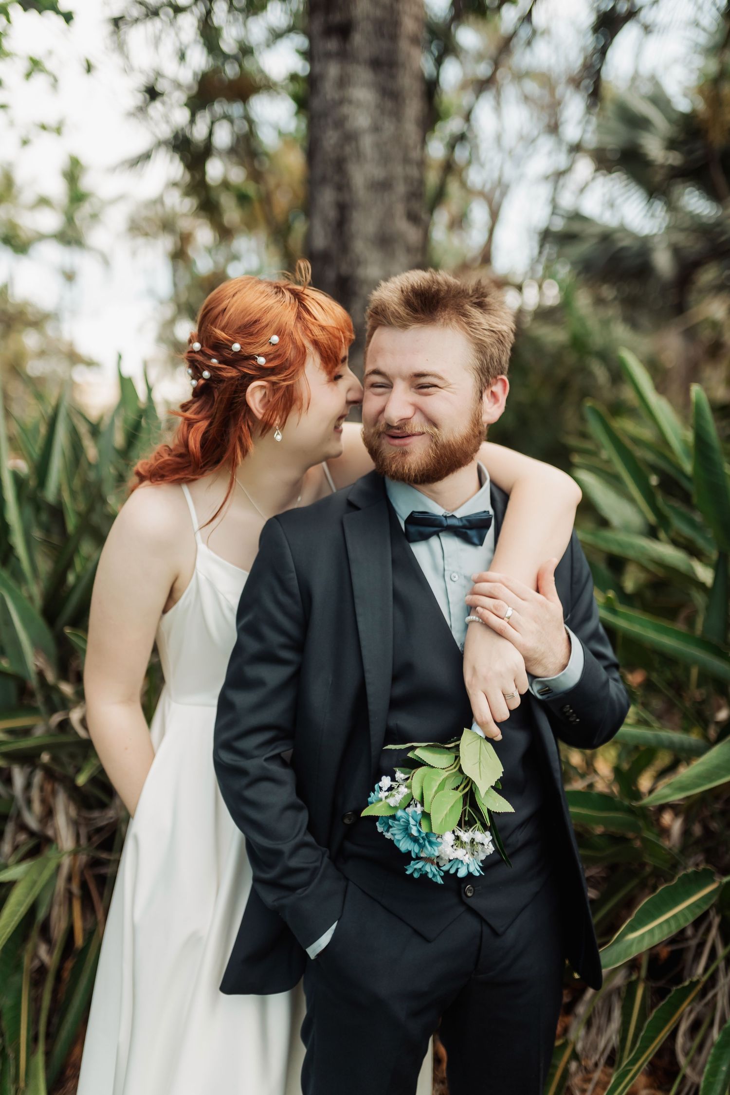 Playful wedding portraits captured against a tropical garden backdrop.
