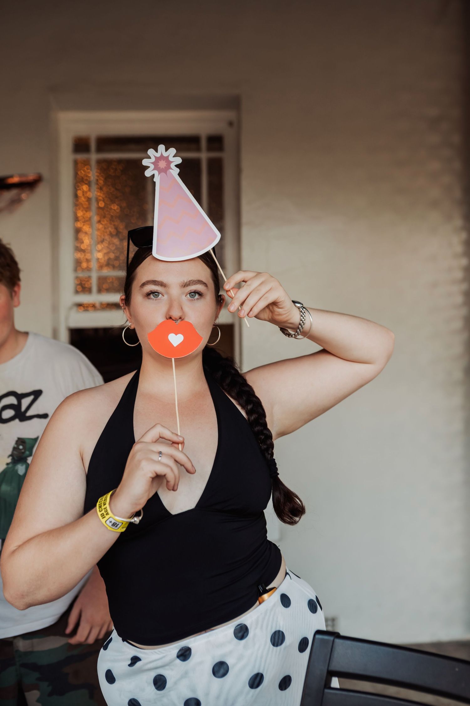 A festive party scene with someone wearing a pink party hat and holding props.