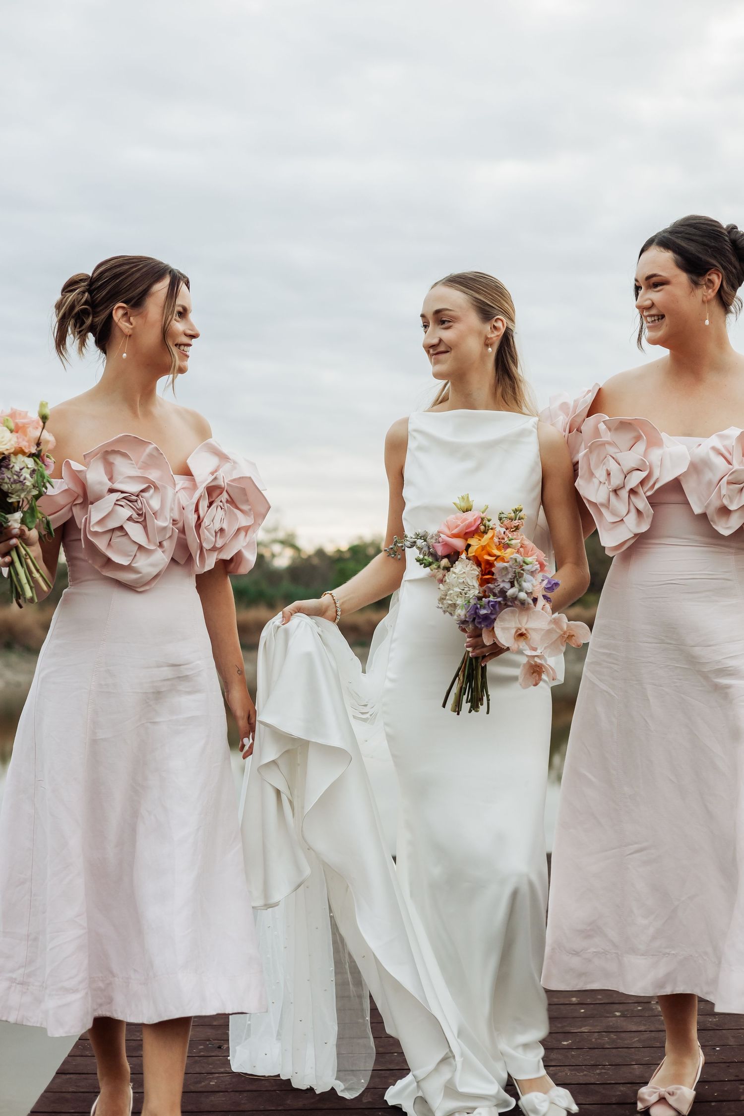 Wedding party in pink and white dresses standing together outdoors.