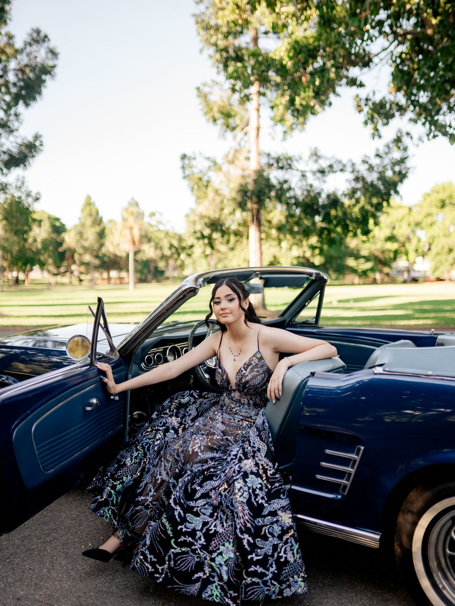 Dramatic fashion shoot with a dark blue classic convertible car in natural lighting.