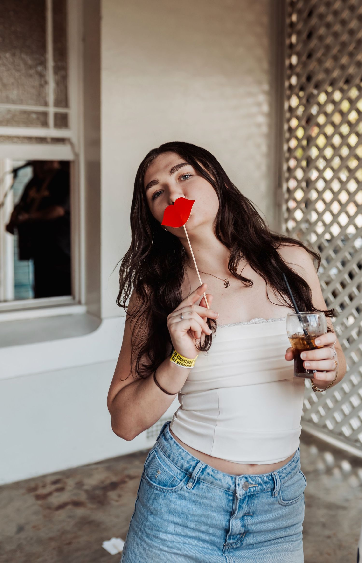 A candid party photo with someone holding a red prop against a white wall background.