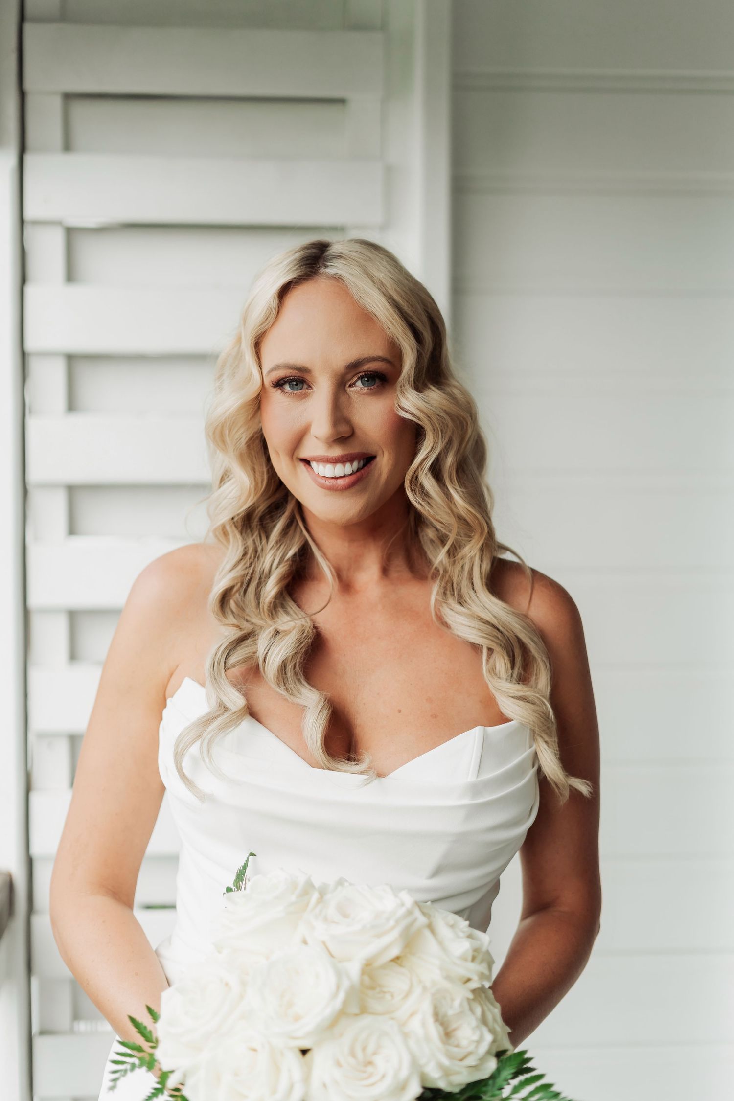 Elegant bridal portrait with white roses bouquet against white background.