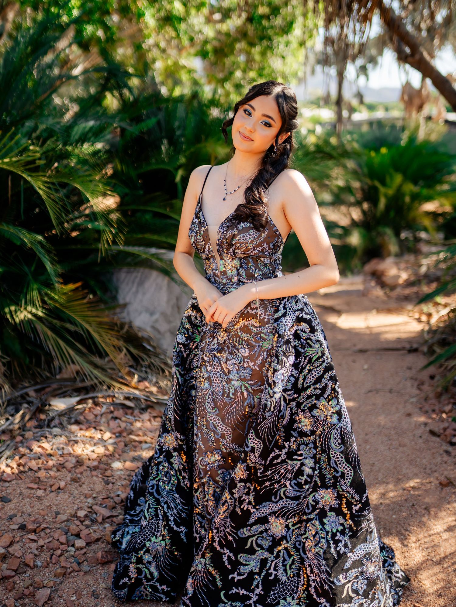 A glamorous evening gown photoshoot in a garden setting with a flowing black and silver dress.