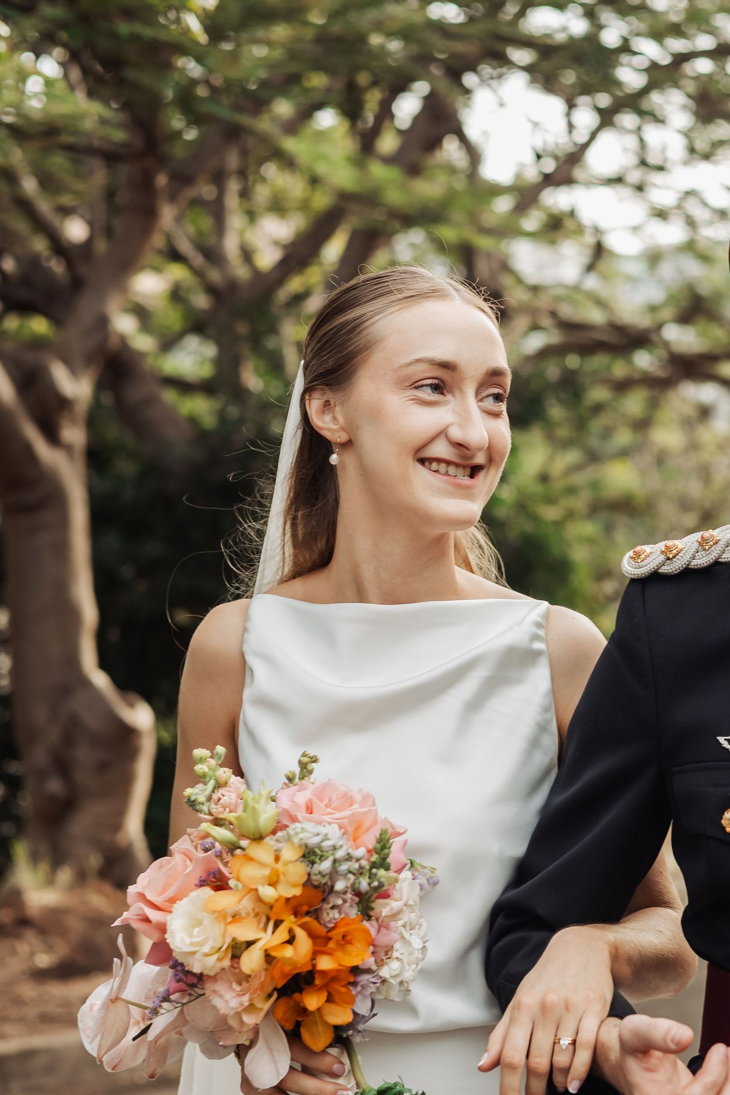 Joyful wedding moment captured outdoors with colorful bouquet and natural lighting.