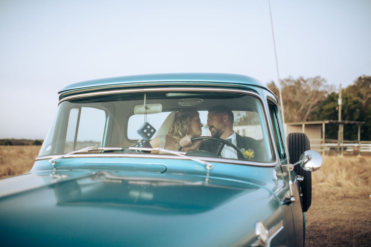 A couple sits in a classic turquoise car on their wedding day. Long Horns Charters Towers