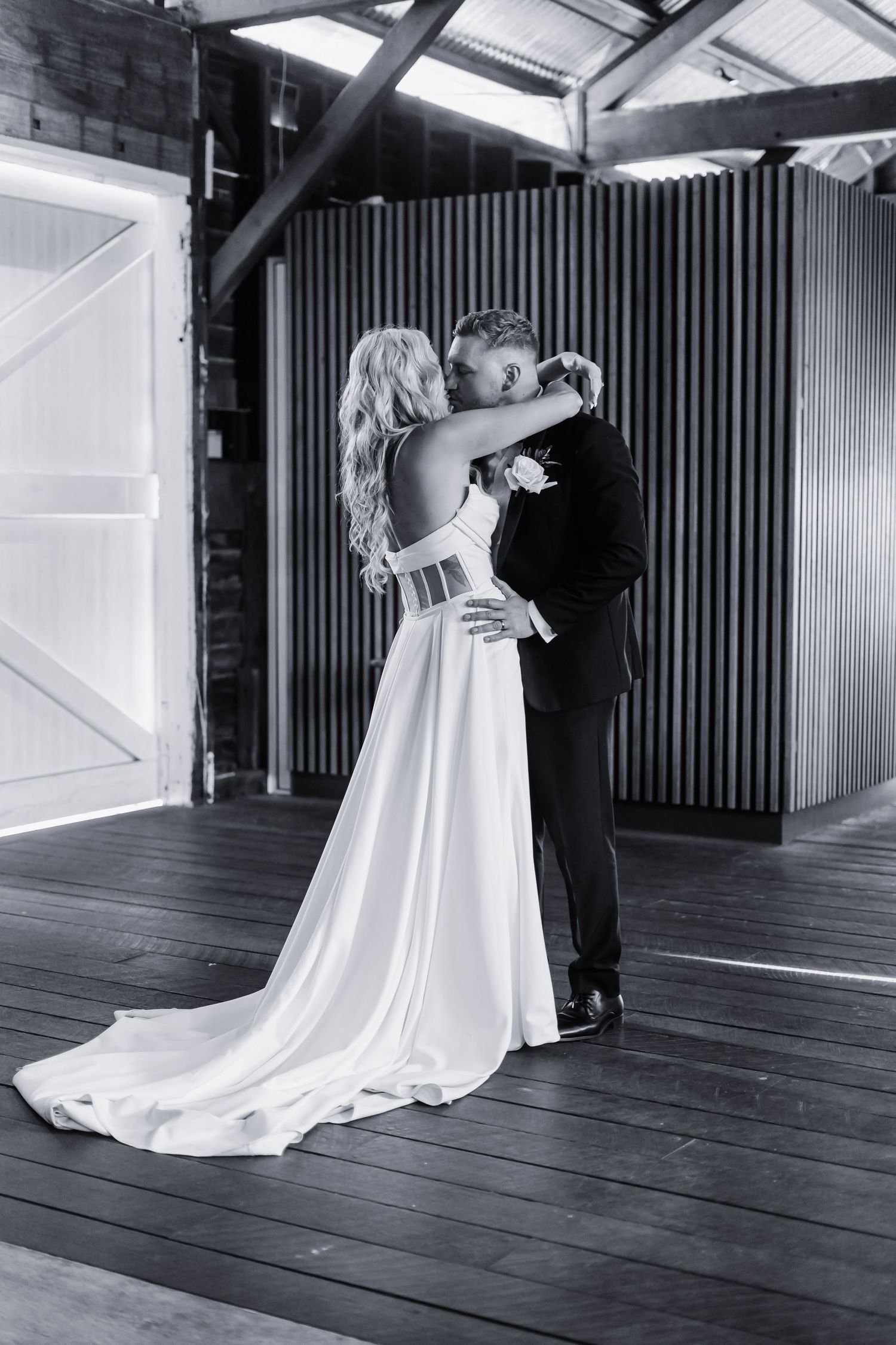 Black and white wedding dance captured in rustic indoor venue.