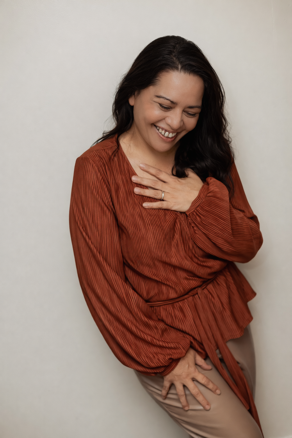 A candid portrait showing genuine emotion in a rust-colored wrap top.
