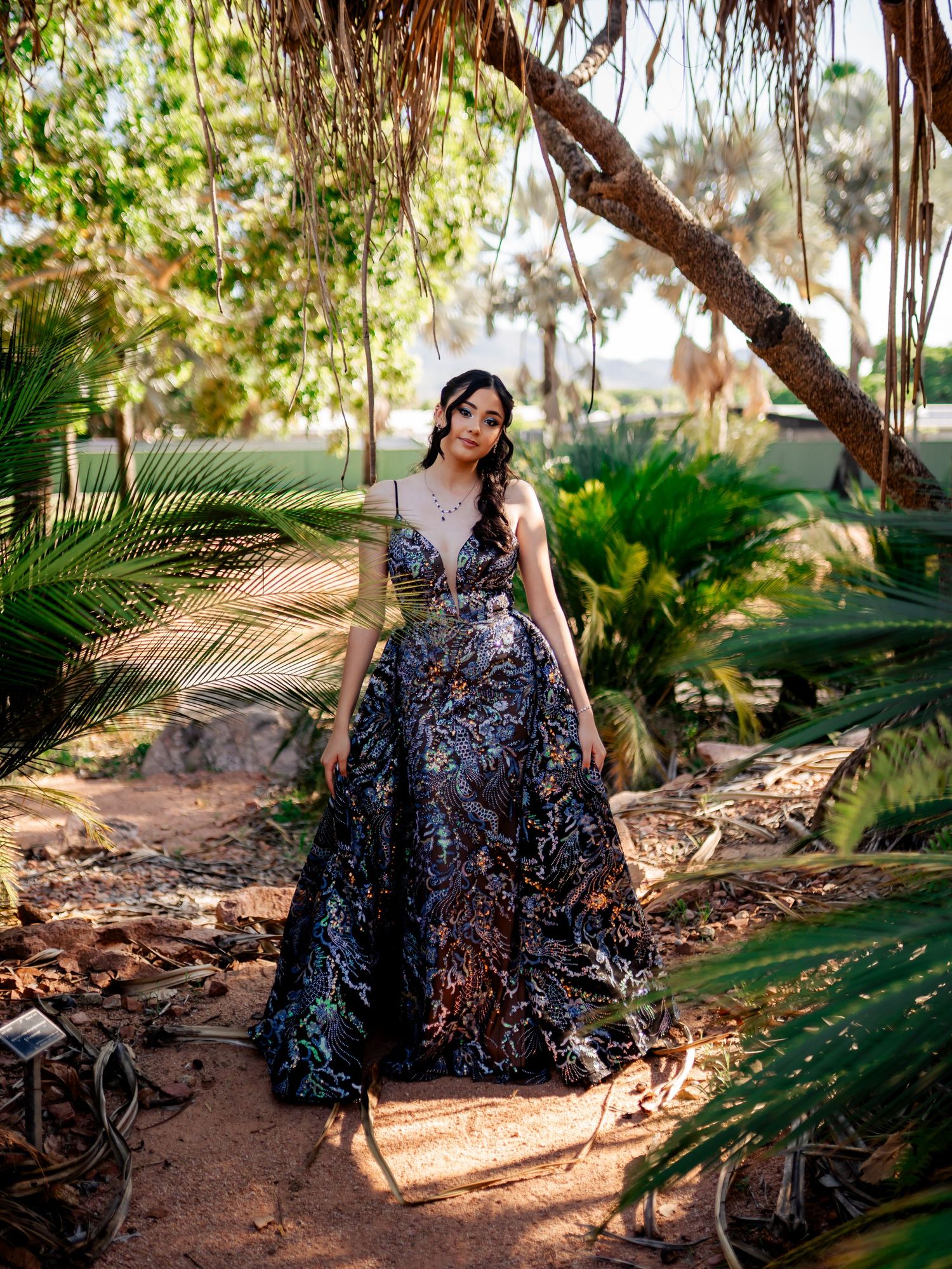 Garden photoshoot featuring dramatic sequined evening gown among palm trees.