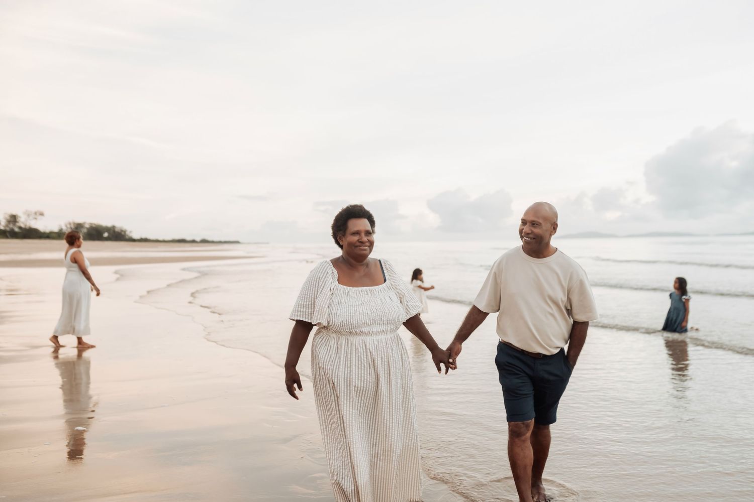Two people strolling together on a peaceful beach during golden hour.