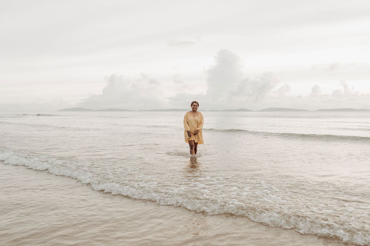 Distant view of person in yellow shirt walking along shoreline.