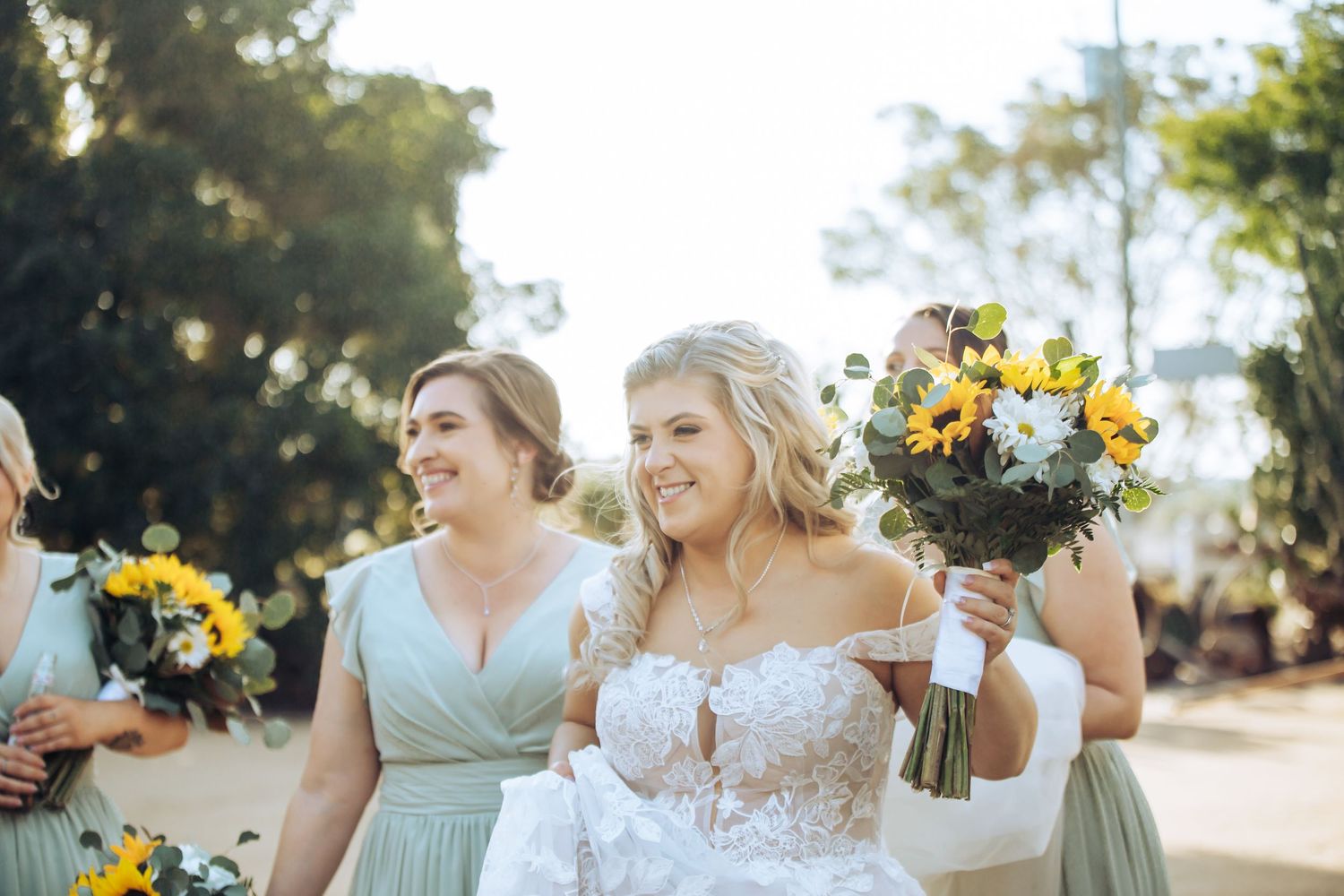 Wedding party members in mint green dresses hold sunflower bouquets outdoors. Long Horns Charters Towers
