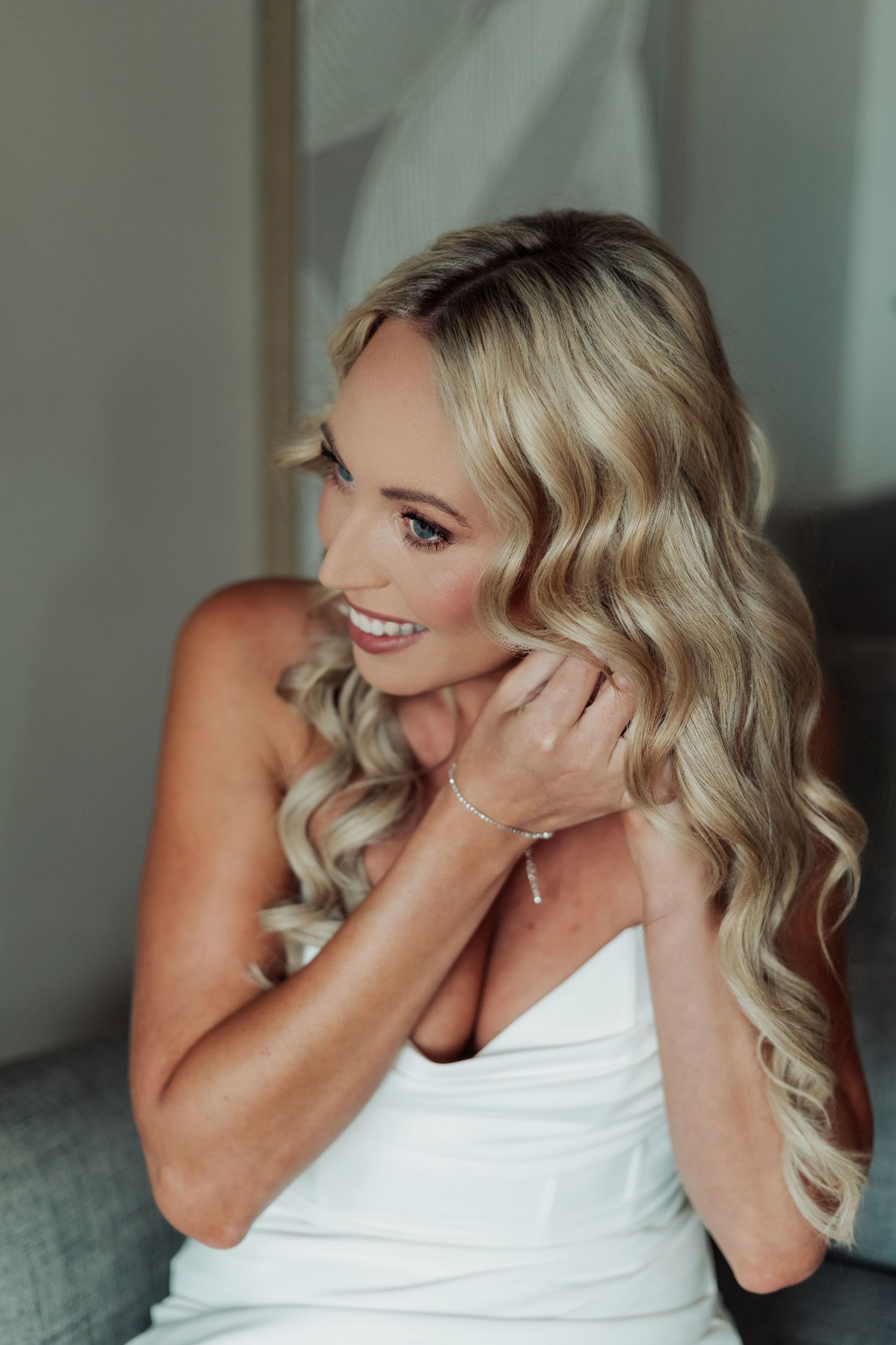 Candid bridal portrait showing joyful laughter in white dress.