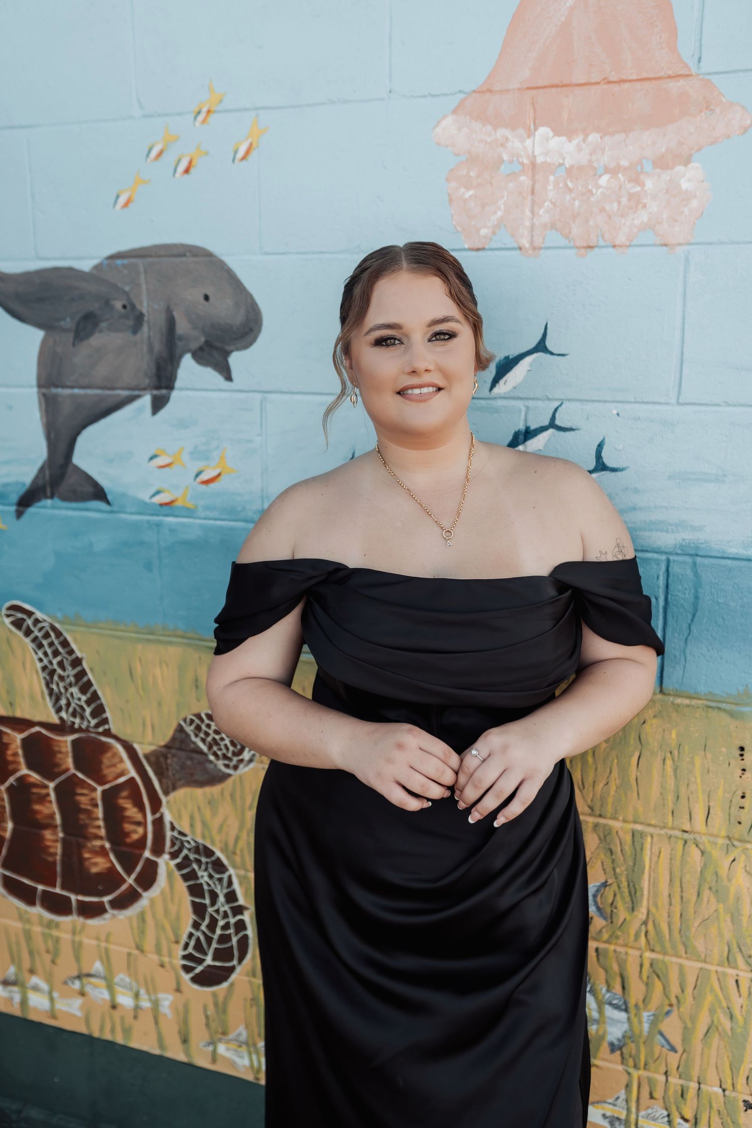 Portrait session against a blue wall with painted ocean mural featuring dolphins and sea turtles.