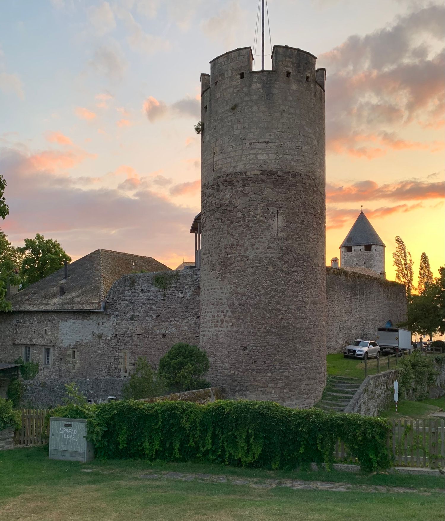 Medieval stone fortress walls and towers at sunset with grassy foreground.
