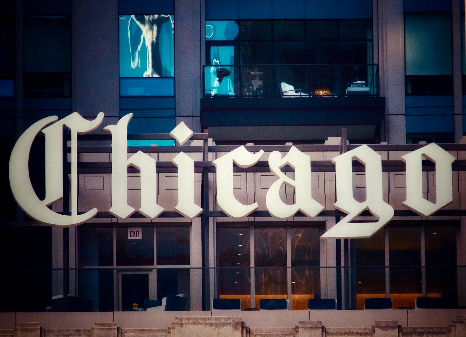 A vintage Chicago Tribune newspaper sign illuminated in white neon letters against a dark urban backdrop.