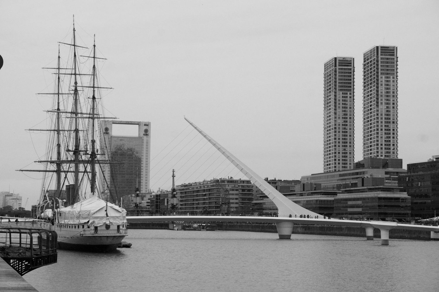 A series of black and white photographs showing historic tall ships docked along a harbor with city buildings in the background.