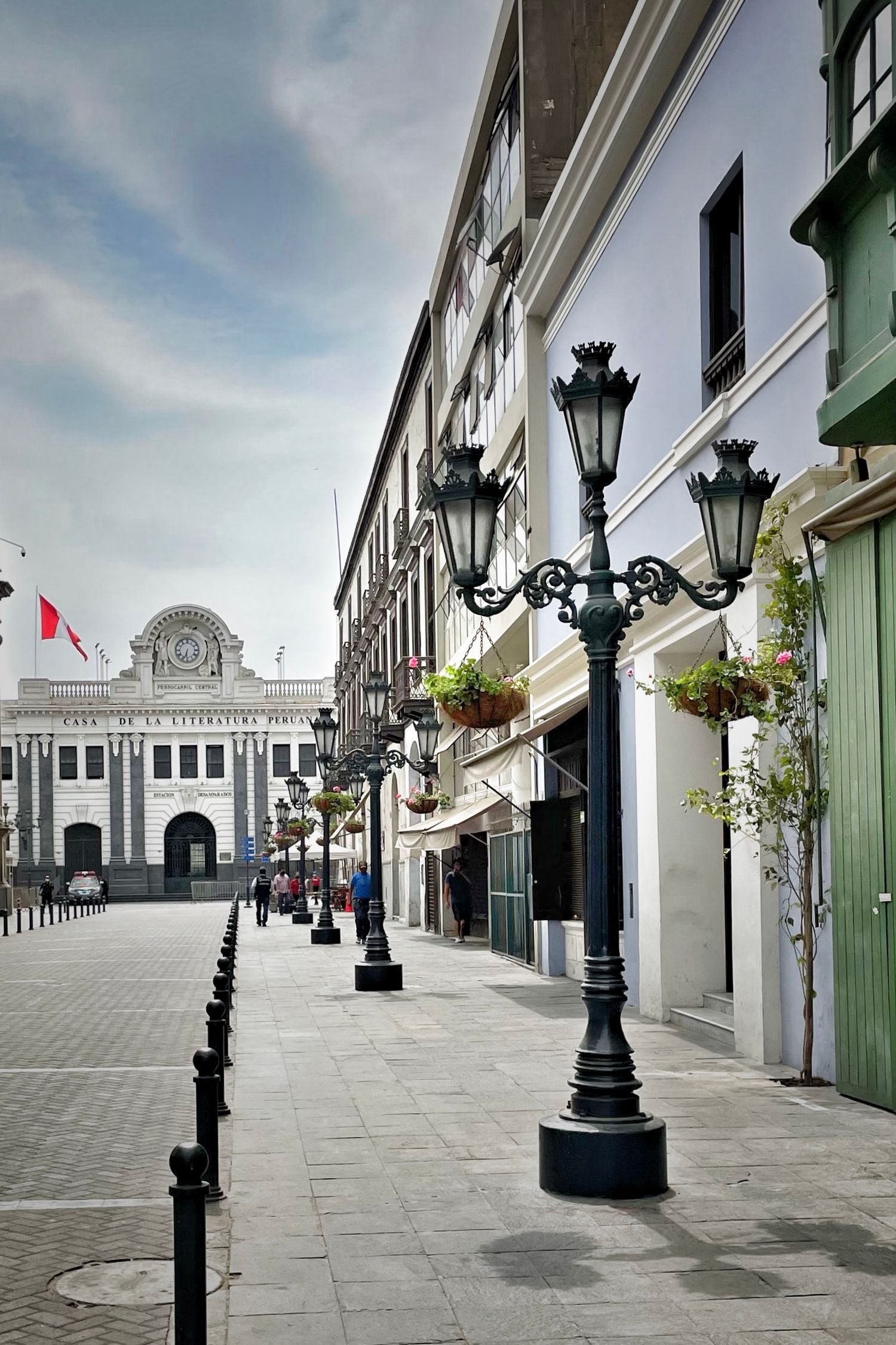 Elegant shopping arcade with ornate lampposts leading to a classical building facade.