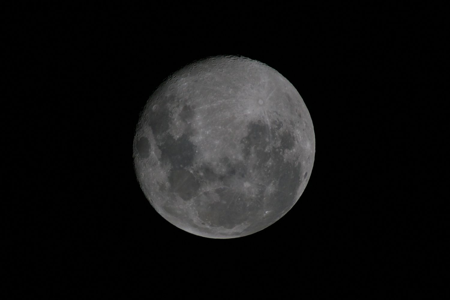 A detailed black and white photograph of a full moon showing its craters and surface features against a dark sky.