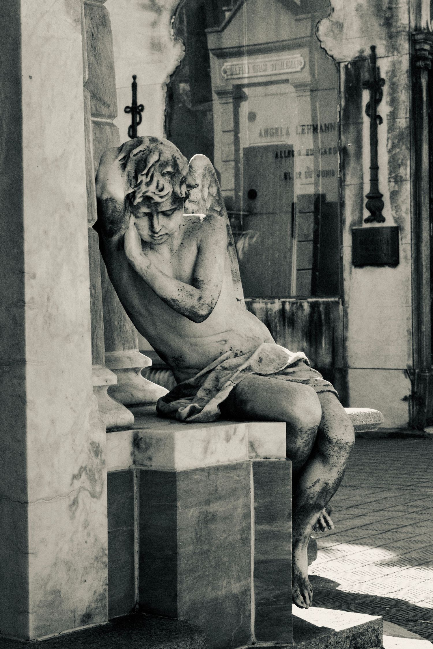 Black and white photograph of ornate stone sculptures displayed in a museum hallway with dramatic lighting.