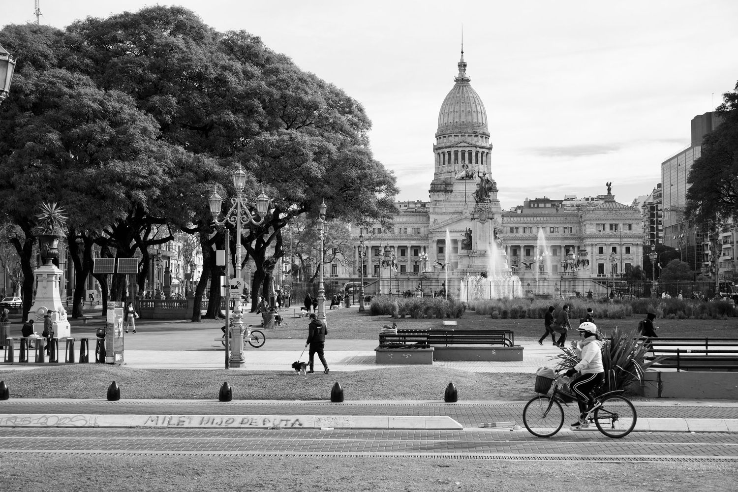 Historic government building with dome seen from multiple angles with cyclists in foreground.