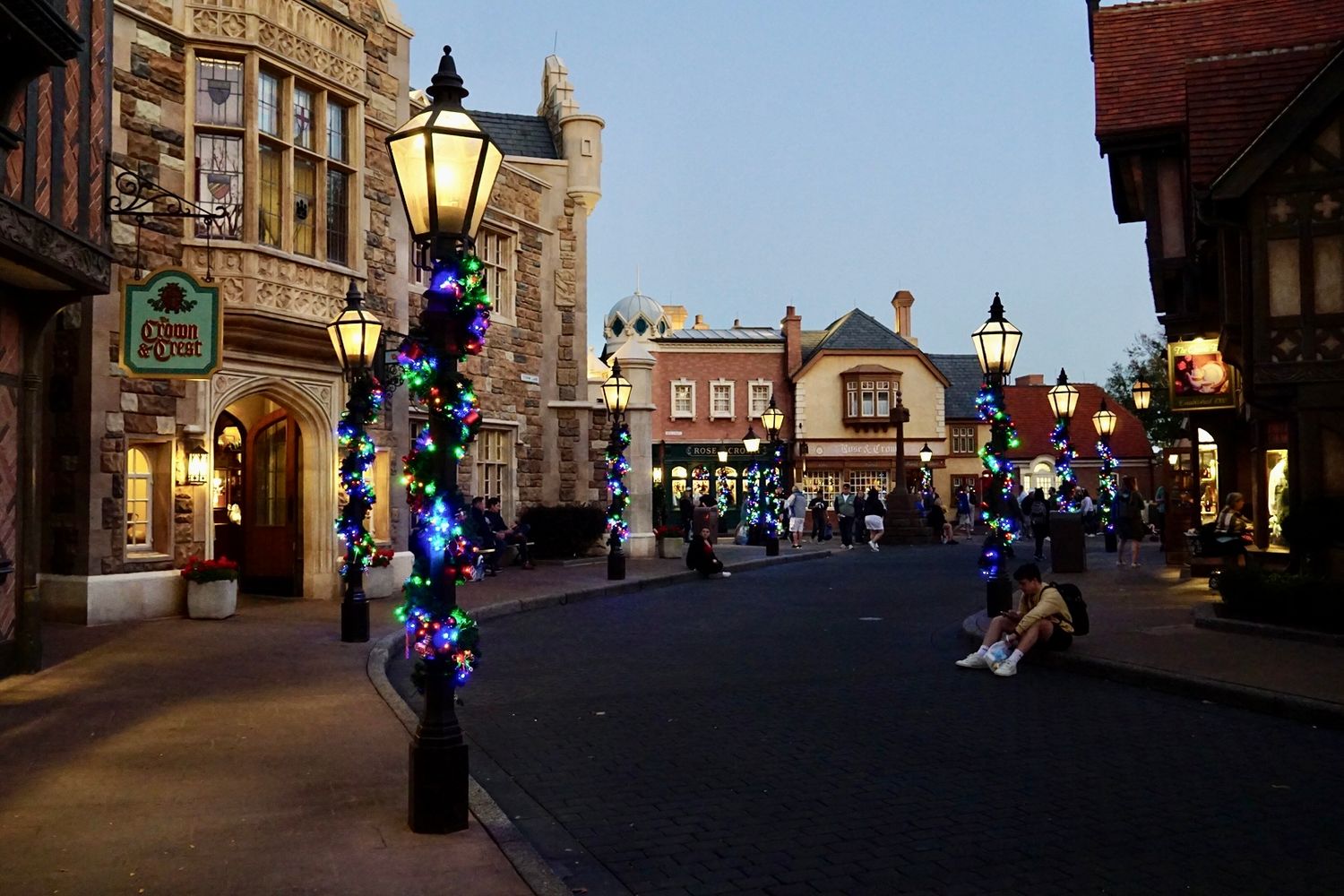 Evening view of a historic shopping district with illuminated lampposts and stone buildings.