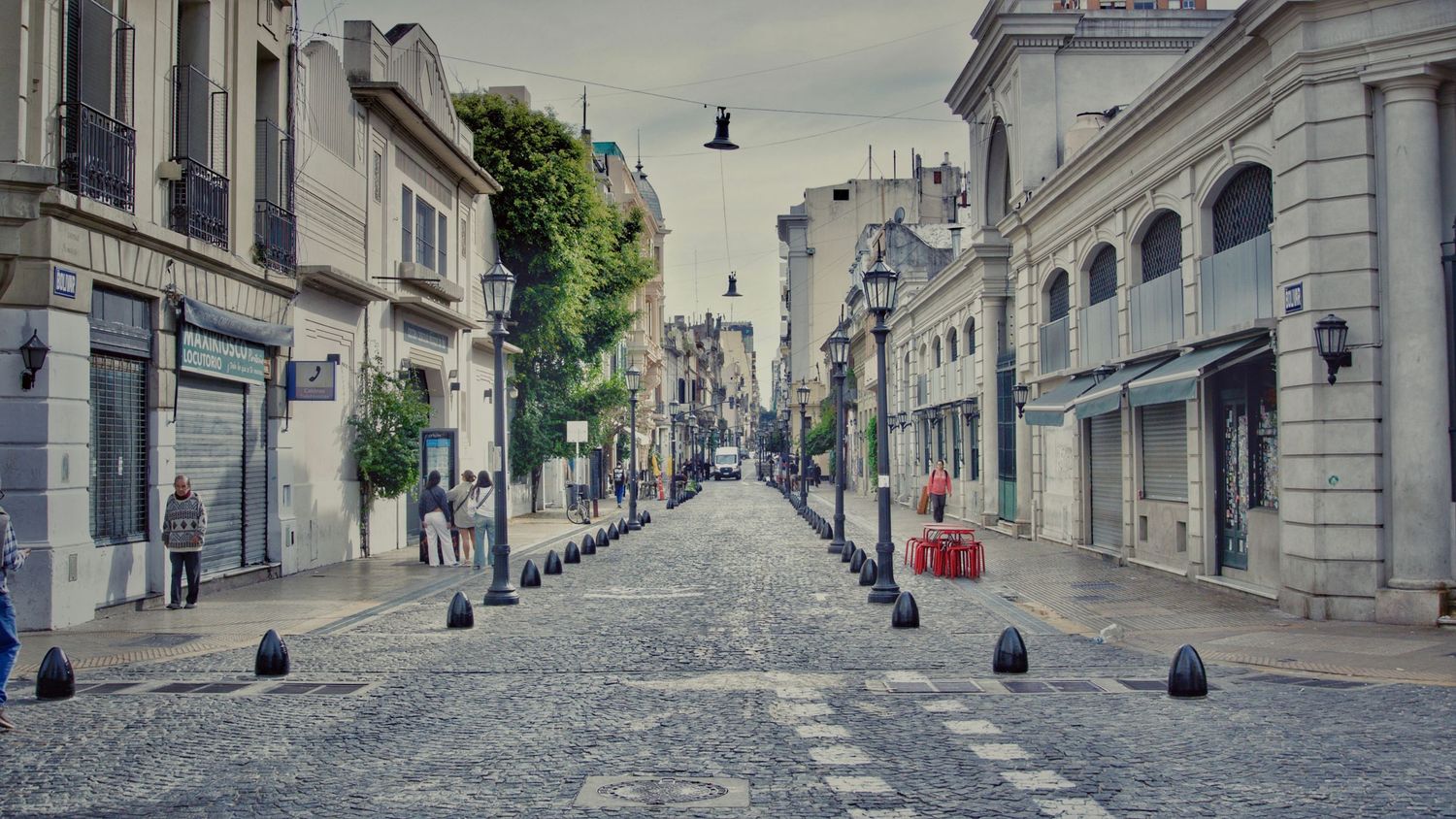 Panoramic view of a historic European cobblestone street with classic architecture and lamp posts.