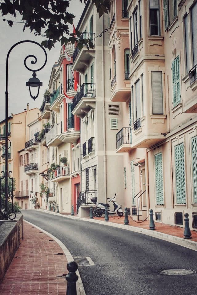 Curved residential street with elegant pastel buildings, ornate balconies, and vintage-style lampposts.