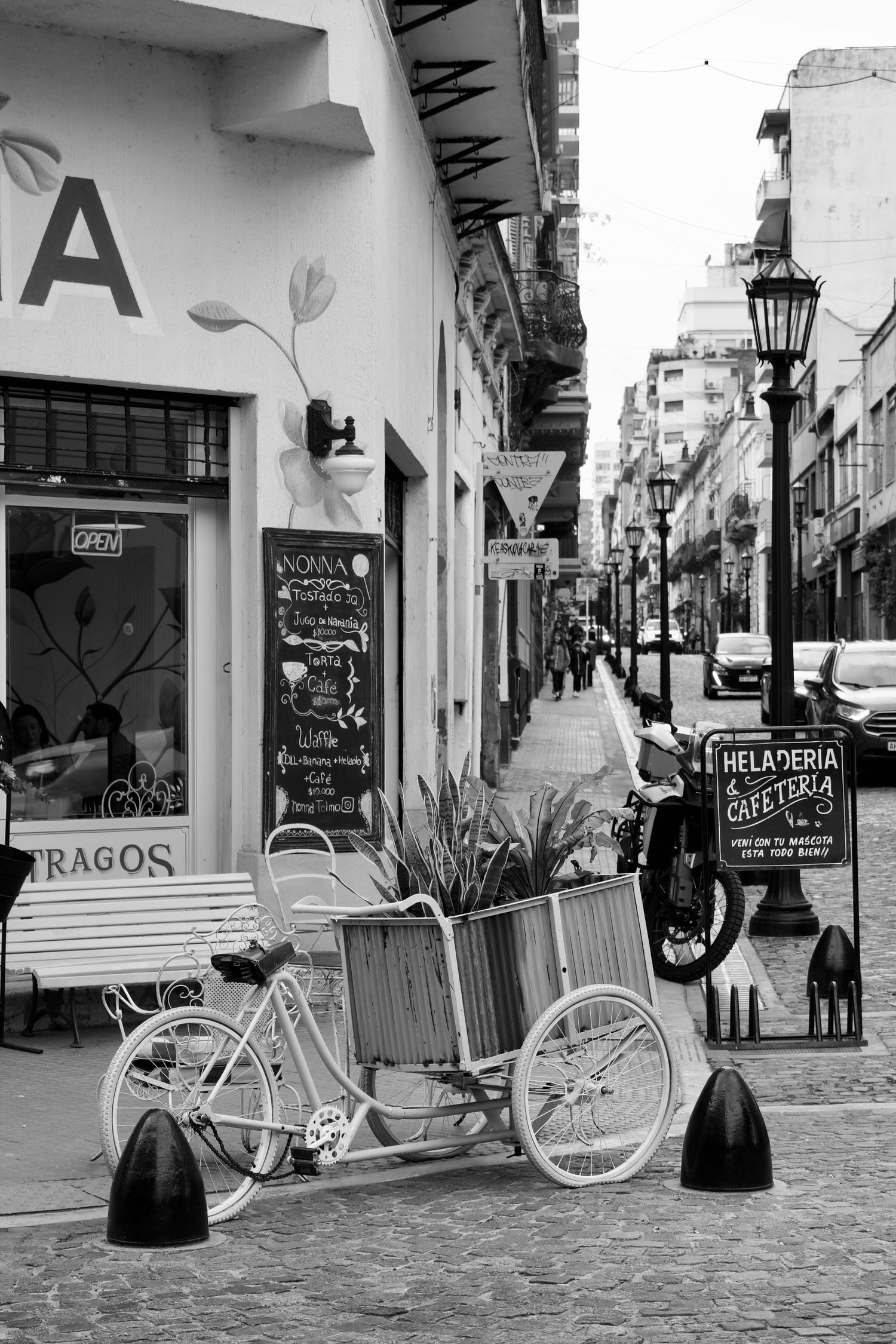 Vintage bicycles parked along a white-walled colonial street with storefronts and hanging signs.