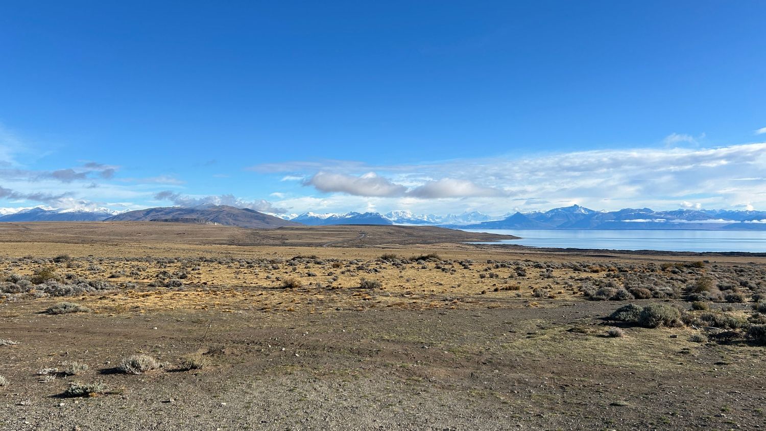 Expansive desert landscape panorama with distant mountains under bright blue skies.