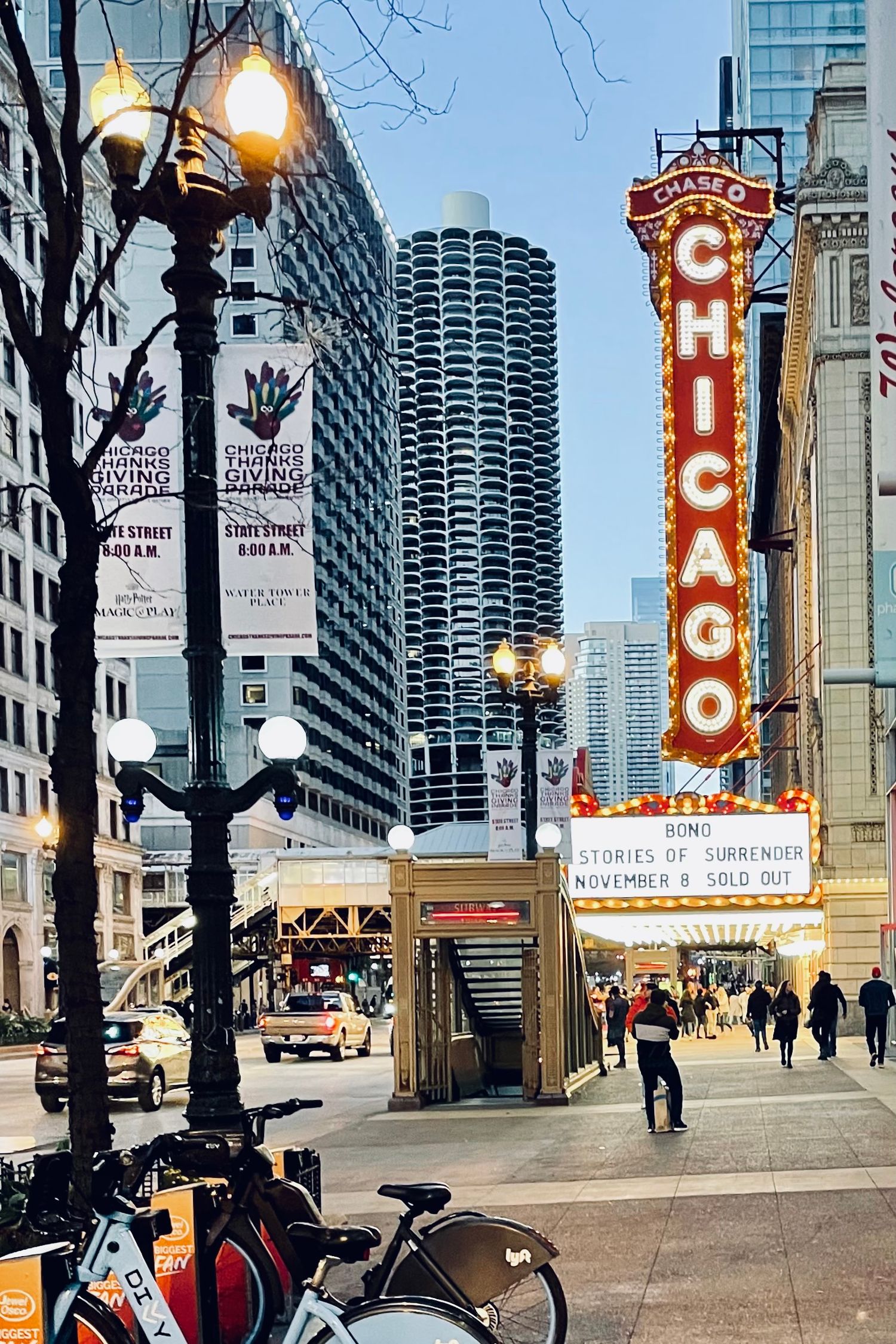 Urban street scene in Chicago with iconic theater marquee signs and high-rise buildings along State Street.