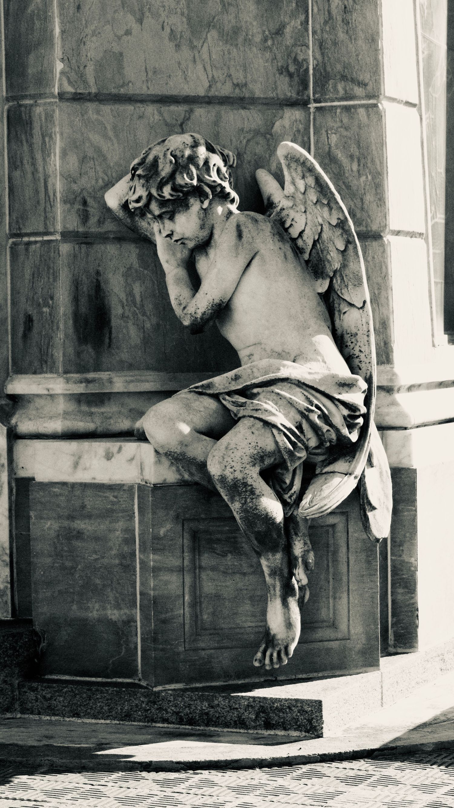 Black and white photo sequence showing a cherub statue mounted on a wall in different angles and perspectives.