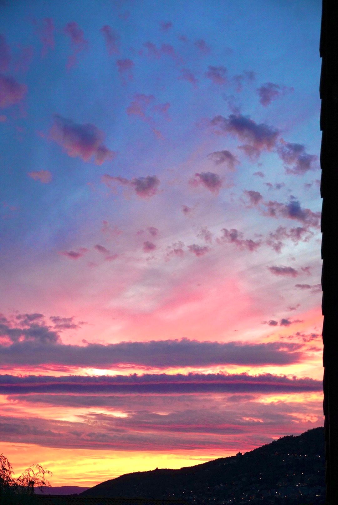 Stunning sunset sky with vibrant pink and purple clouds stretching across the horizon over mountain silhouettes.