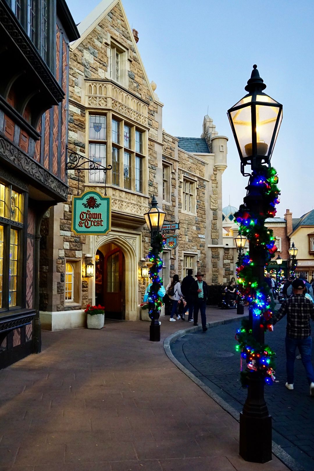 Stone-paved shopping street with decorative lampposts adorned with blue Christmas lights and historic architecture.