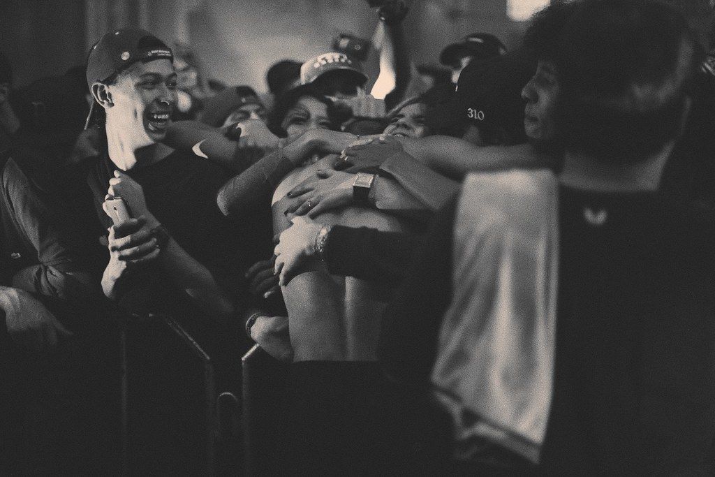 Plateia com as mãos erguidas durante o show, em fotografia em preto e branco.